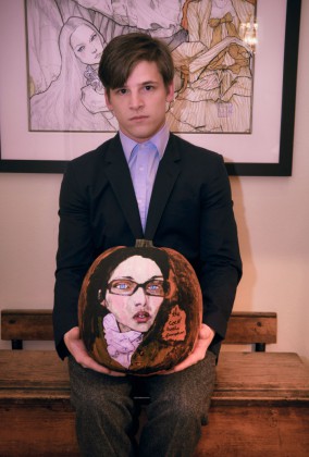 A portrait of Danny Roberts holding a pumpkin he painted of Model Coco Rocha